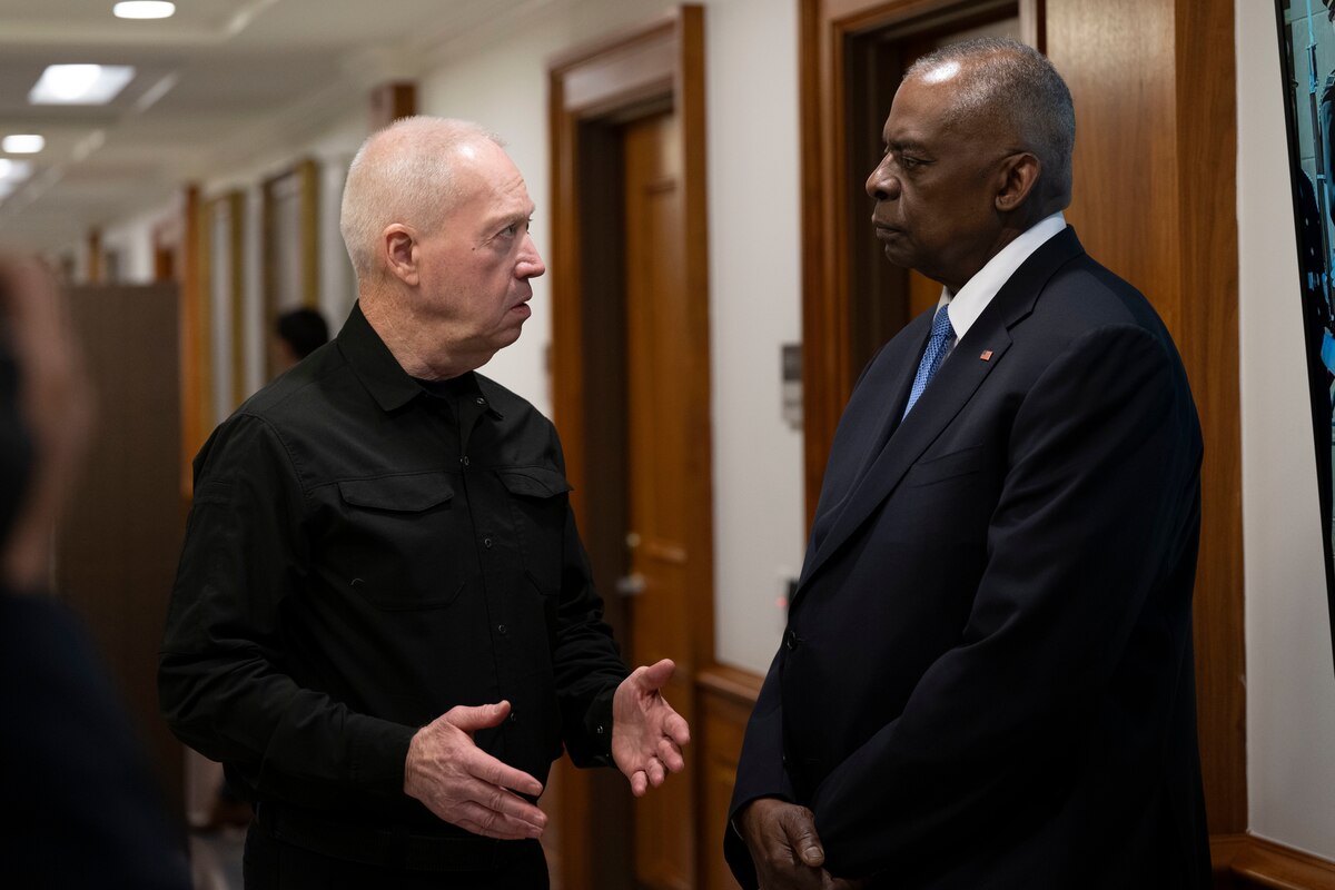 Two men speak while standing in a building.