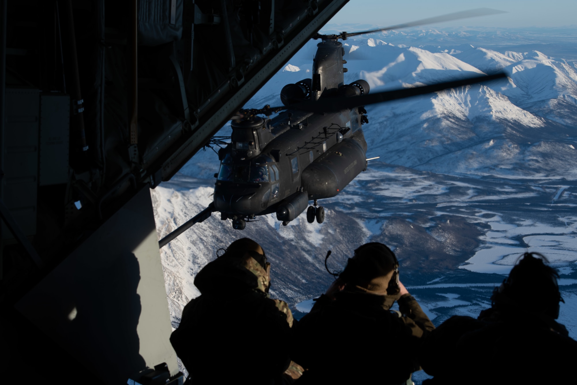 U.S. service members from the 160th Special Operations Aviation Regiment (Airborne), 6th Special Operations Squadron and 109th Airlift Wing watch a MH-47G Special Operations Aircraft assigned to the 160th Special Operations Aviation Regiment (Airborne), refuel mid-air during Arctic Edge 24(AE24) over the Alaskan wilderness, March 2, 2024. During AE24, more than 400 joint and allied Special Operators trained in extreme cold conditions to sharpen SOF readiness across unique specialties like long range fires and movements, special reconnaissance, rapid resupply, personnel recovery, and medical care in the austere Arctic environment. (U.S. Air Force photo by Senior Airman Drew Cyburt)