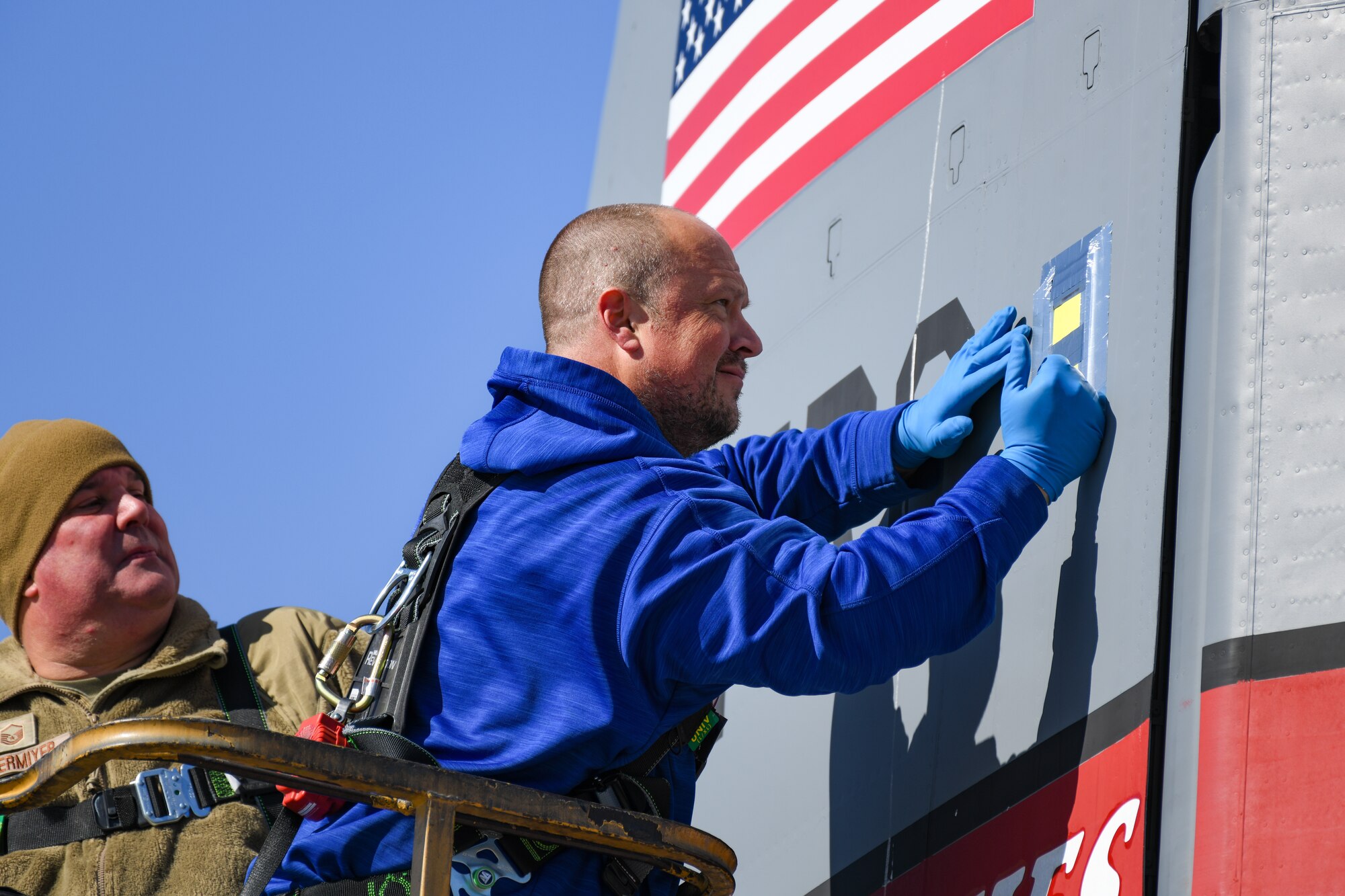 Matthew Kilmer, a C-130 system engineer from the Air Logistics Complex C-130 System Program Office at Warner Robins Air Force Base, Georgia, fastens a droplet sample card to the tail of a C-130J-30 Super Hercules aircraft at Youngstown Air Reserve Station, Ohio, March 25, 2024.
