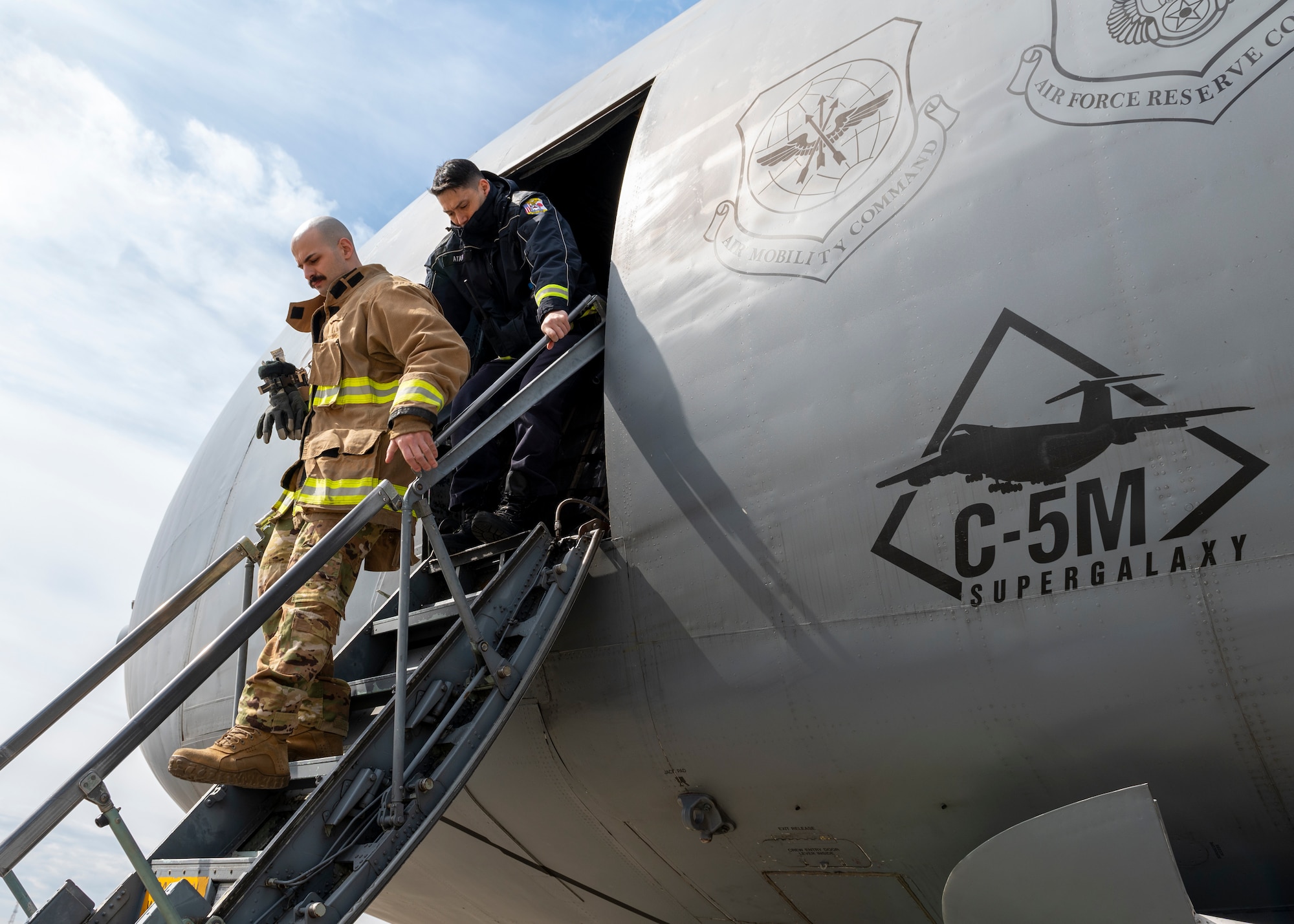 Firefighters, walks down the ladder of a C-5M Super Galaxy, assigned to the 60th Air Mobility Wing, Travis Air Force Base, CA, at Yokota Air Base