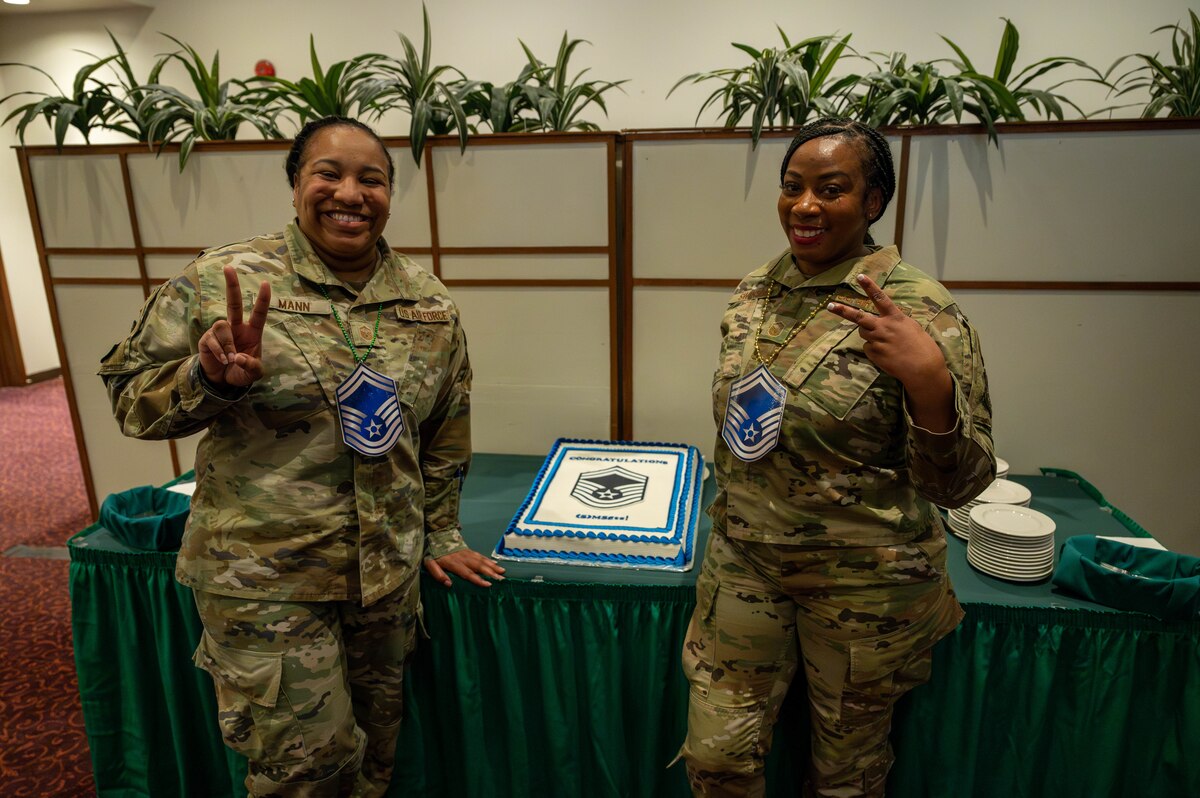 Two service members pose in front of a cake.