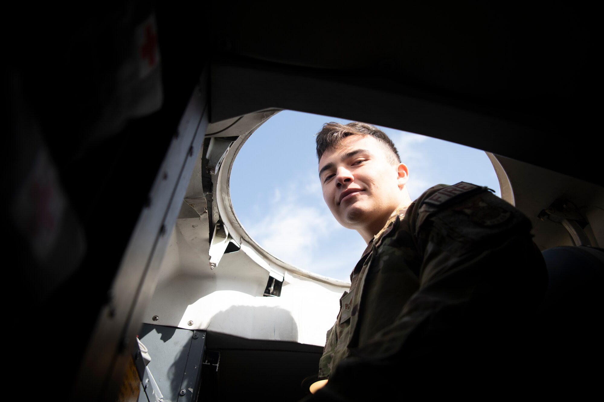 A firefighter poses for photo while climbing a ladder inside a C-5M Super Galaxy.