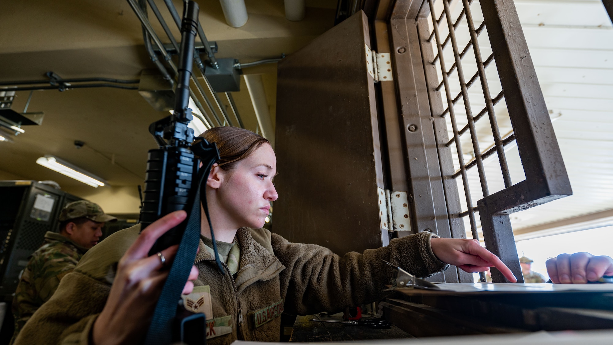 Senior Airman Mackenzie Garrick instructs an Airman on where to sign a form prior to distributing an M4 carbine rifle.