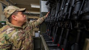 Staff Sgt. Daniel Lopez picks up an M4 carbine rifle while distributing weapons.