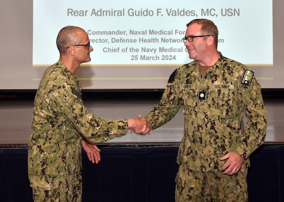 JOINT BASE SAN ANTONIO-FORT SAM HOUSTON – (March 25, 2024) – Rear Adm. Guido Valdes, commander, Naval Medical Forces Pacific (NMFP), presents his command coin to Cmdr. Brendan O’Brien assigned to Naval Medical Research Unit (NAMRU) San Antonio during a townhall meeting held at the Military and Family Readiness Center. Valdes, who serves as the Chief of Navy Medical Corps, has oversight of 10 Navy Medicine Readiness and Training Commands on the West Coast and Pacific Rim as well as Navy Medicine's eight global research labs. Valdes also serves under the Defense Health Agency (DHA) as the director of the Defense Health Network Pacific Rim where he oversees the delivery and integration of healthcare at nine medical treatment facilities (MTF) on the West Coast and Pacific Rim. NAMRU San Antonio’s mission is to conduct gap driven combat casualty care, craniofacial, and directed energy research to improve survival, operational readiness, and safety of Department of Defense (DoD) personnel engaged in routine and expeditionary operations. It is one of the leading research and development laboratories for the U.S. Navy under the DoD and is one of eight subordinate research commands in the global network of laboratories operating under the Naval Medical Research Command in Silver Spring, Md. (U.S. Navy photo by Burrell Parmer, NAMRU San Antonio Public Affairs/Released)