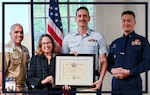 U.S. Coast Guard and United States Naval Community College officials pose for a photograph with the first-ever USNCC graduate. Shown from left to right: Coast Guard Senior Chief Petty Officer Ryan Erpelding; Navy Command Master Chief Jordan Rosado; Randi Cosentino, president of USNCC; Petty Officer 2nd Class Merrill Magowan; and Capt. Taylor Lam, commander of Sector San Francisco.