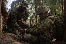 A U.S. Navy sailor, left, with Battalion Landing Team 1/1, 31st Marine Expeditionary Unit medically assesses a soldier with the 2nd Amphibious Rapid Deployment Regiment, Japan Ground Self-Defense Force as he applies a tourniquet to his leg for a simulated wound during tactical combat casualty care training for Iron Fist 24 at Camp Hansen, Okinawa, Japan, Feb. 26, 2024.