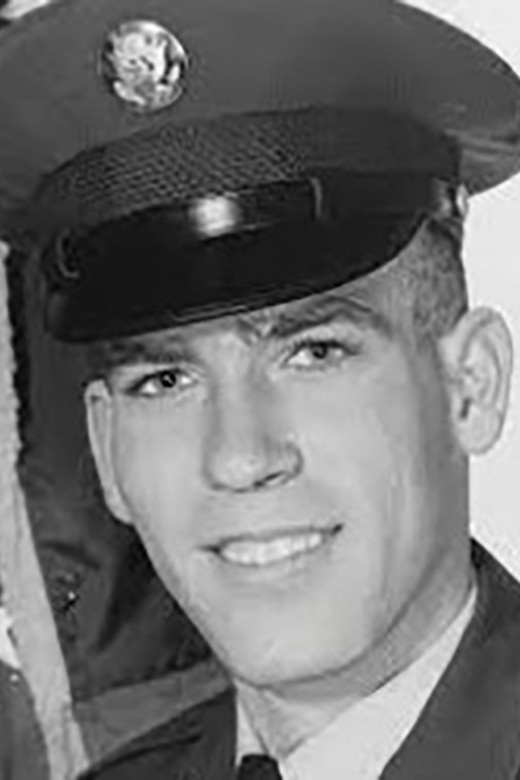 Close-up of a uniformed service member smiling for a black and white photo.