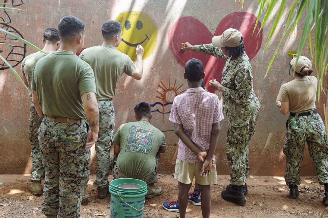 U.S. Marines assigned to the 15th Marine Expeditionary Unit and Sailors assigned to the amphibious transport dock USS Somerset (LPD 25) paint a mural with children from a foster home during a community relations event during Exercise Tiger TRIUMPH in Visakhapatnam, India, March 22, 2024. Tiger TRIUMPH is a U.S.-India tri-service amphibious exercise focused on humanitarian assistance and disaster relief readiness and interoperability. Tiger TRIUMPH enables U.S. and Indian Armed Forces to improve interoperability and bilateral, joint, and service readiness in the Indian Ocean region and beyond to better achieve mutual regional security objectives. (U.S. Marine Corps photo by 1st Lt. Robert Nanna)