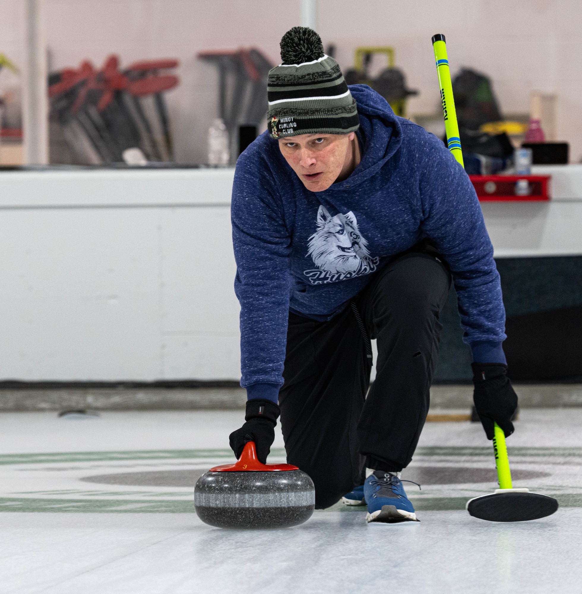 U.S. Air Force Maj. Zachary Jones, 91st Operations Group wing operations center director, executes the delivery of a curling stone at the Minot Curling Club, Minot, North Dakota, March 19, 2024. Jones and his team, Sweep Dreams, competed in and won the Minot AFB Curling League championship game. (U.S. Air Force photo by Airman 1st Class Kyle Wilson)