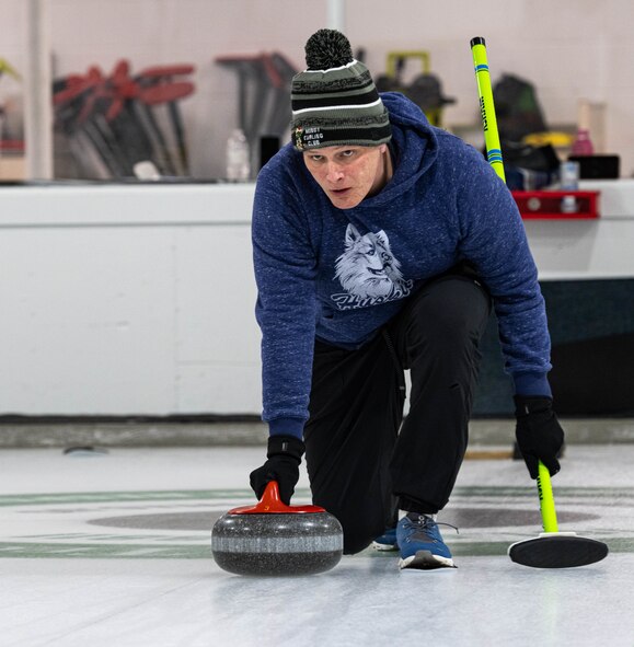 U.S. Air Force Maj. Zachary Jones, 91st Operations Group wing operations center director, executes the delivery of a curling stone at the Minot Curling Club, Minot, North Dakota, March 19, 2024. Jones and his team, Sweep Dreams, competed in and won the Minot AFB Curling League championship game. (U.S. Air Force photo by Airman 1st Class Kyle Wilson)