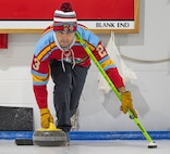 U.S. Air Force Capt. Steven Lawless, 23rd Bomb Squadron weapon systems officer, prepares to execute the delivery of a curling stone at the Minot Curling Club, Minot, North Dakota, March 19, 2024. Lawless used his broom for stability during the process of delivering the stone. (U.S. Air Force photo by Airman 1st Class Kyle Wilson)