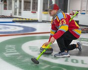 U.S. Air Force Master Sgt. Dalton Helveston, 5th Operations Support Squadron functional manager, executes the delivery of a curling stone at the Minot Curling Club, Minot, North Dakota, March 19, 2024. Helveston and his teammates took turns delivering the curling stone throughout the course of the game. (U.S. Air Force photo by Airman 1st Class Kyle Wilson)