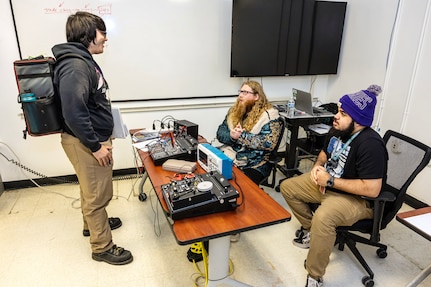 Casey Harris, welder, Shop 26, Welders, talks with Nicholas Haskins, apprentice instructor, and Riley Morris, mechanic, both Shop 06, Tool Mechanics, Maintenance Logistics, March 13, 2024, during an Apprenticeship Knowledge Fair in Building 460 at Puget Sound Naval Shipyard & Intermediate Maintenance Facility in Bremerton, Washington. (U.S. Navy photo by Jeb Fach)