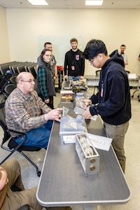 Kevin Berg, apprentice instructor, Shop 31, Inside Machinist, outlines the opportunities available for Denzel Vasquez, rigger, Code 740, Riggers, March 13, 2024, during an Apprenticeship Knowledge Fair in Building 460 at Puget Sound Naval Shipyard & Intermediate Maintenance Facility in Bremerton, Washington. (U.S. Navy photo by Jeb Fach)