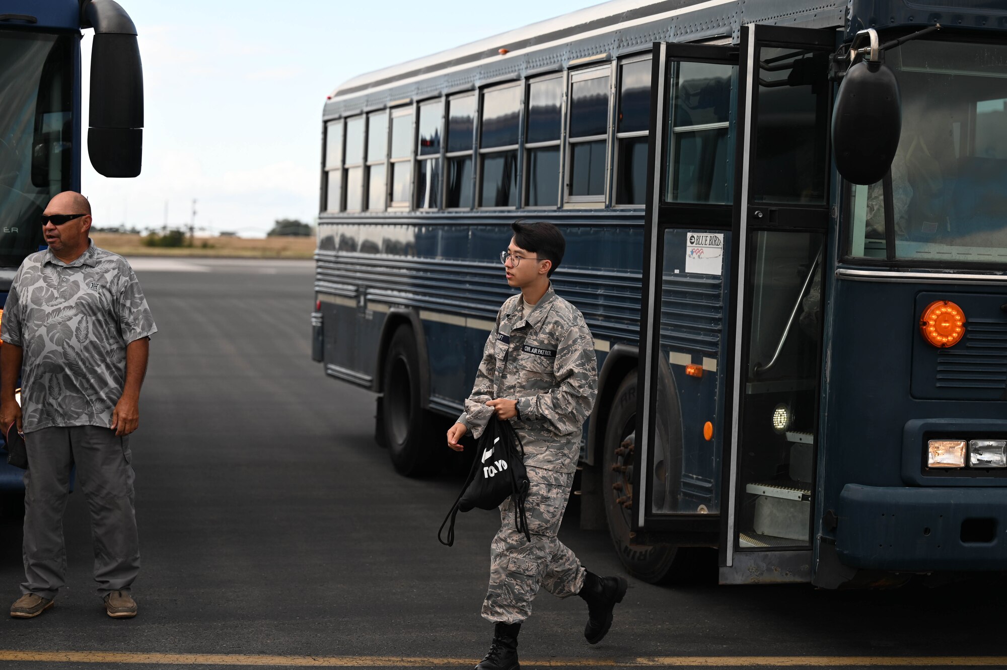 kid walks off a buss onto a flight line for a flight.