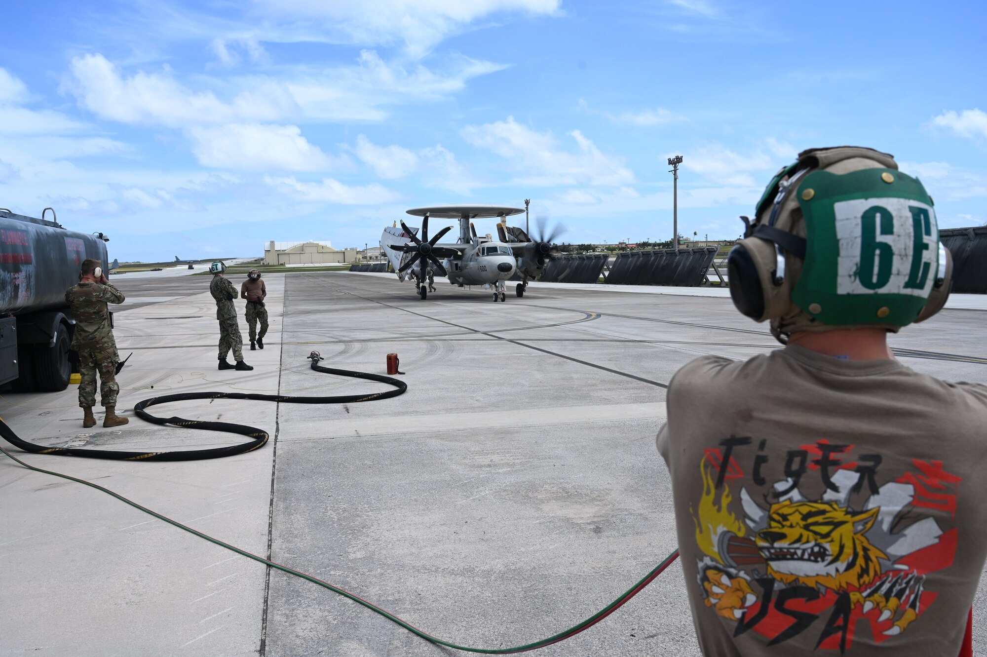 Airmen and Sailors observe a E-2D Hawkeye aircraft taxi on the flightline.