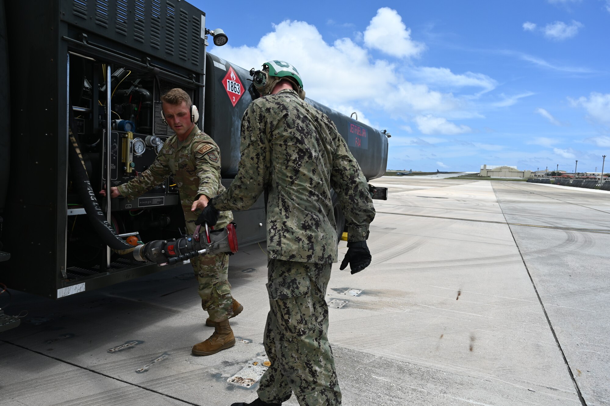 An Airman and a Sailor work on pulling back the refueling equipment.