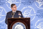 A Space Force general speaks at a lectern to a seated audience.