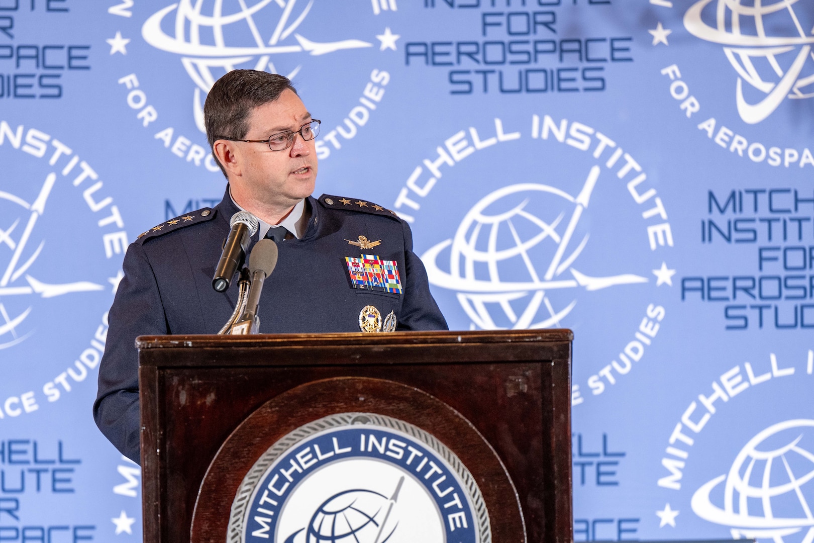 A Space Force general speaks at a lectern to a seated audience.