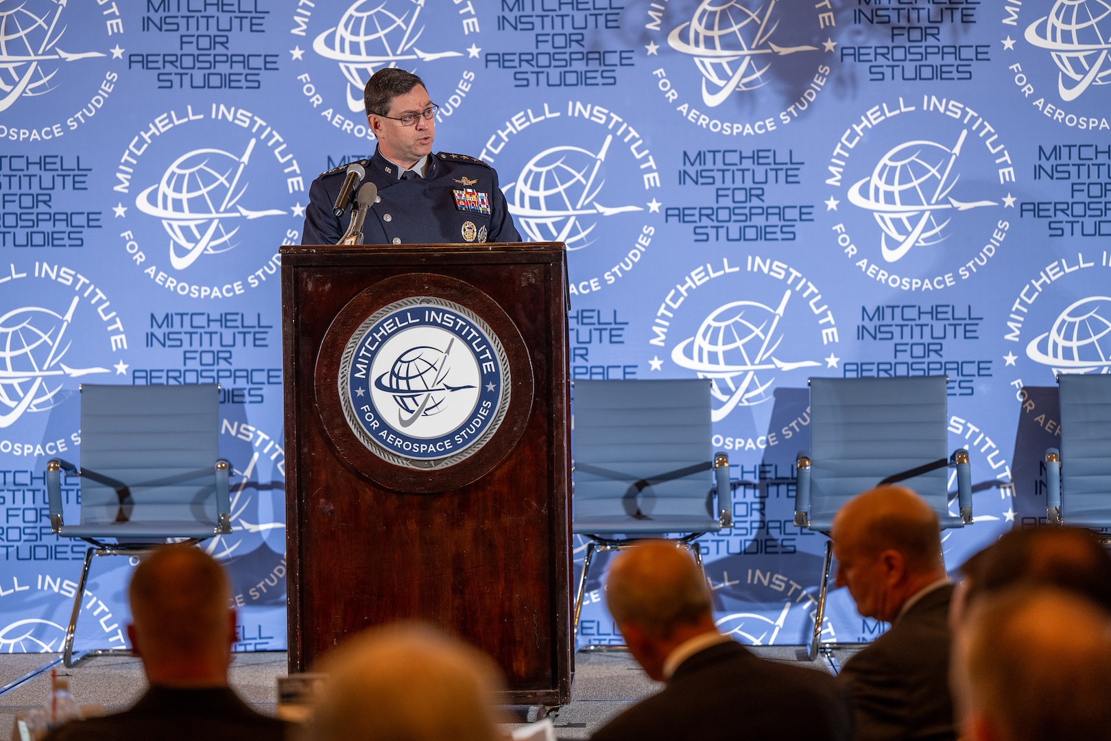 A Space Force general speaks at a lectern to a seated audience.