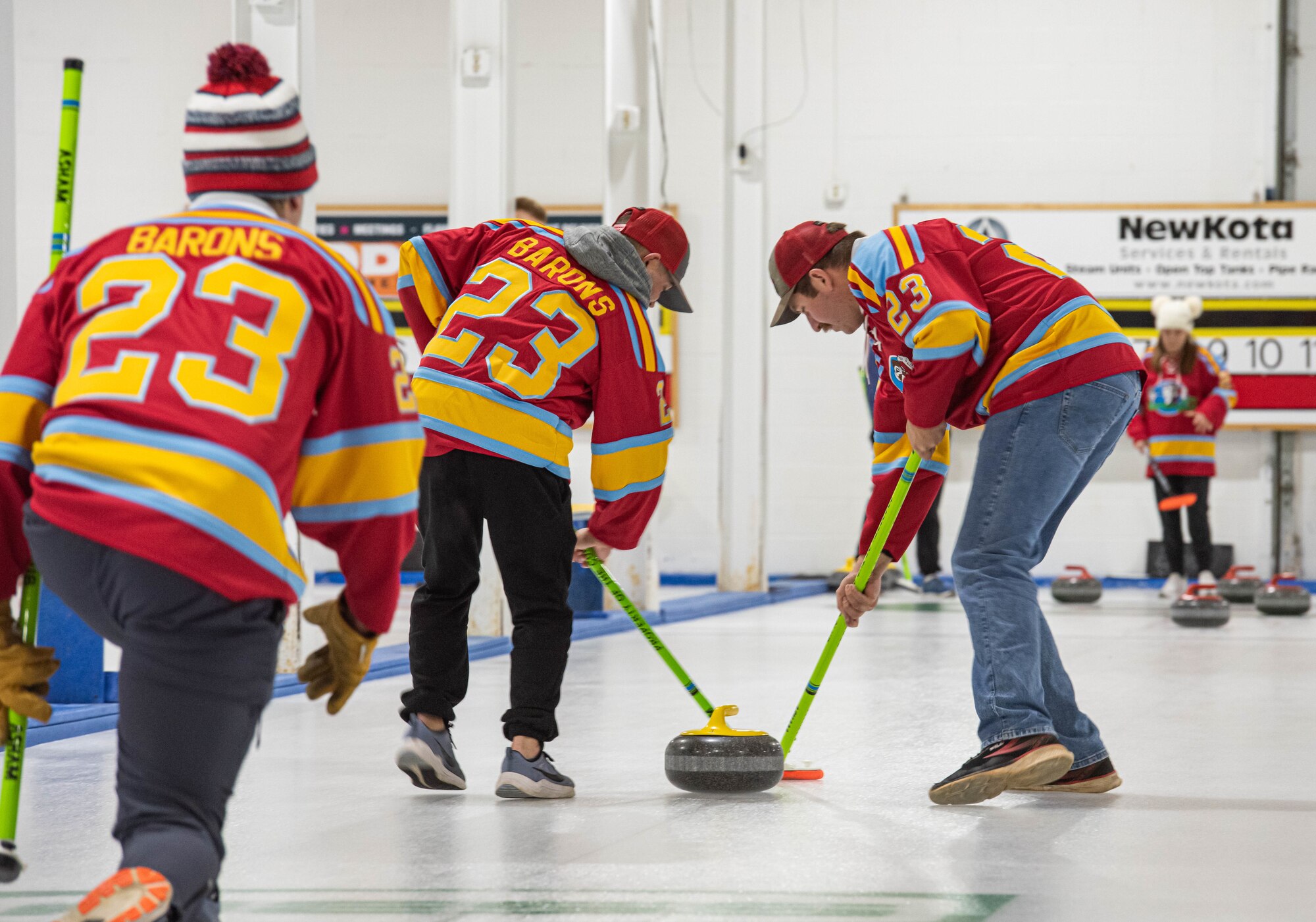 Members of the Lobstahs curling team execute the delivery of a curling stone at the Minot Curling Club, Minot, North Dakota, March 19, 2024. The delivery, or throw, is the process of sliding the curling stone down the sheet of ice and directing it towards the target area. (U.S. Air Force photo by Airman 1st Class Kyle Wilson)