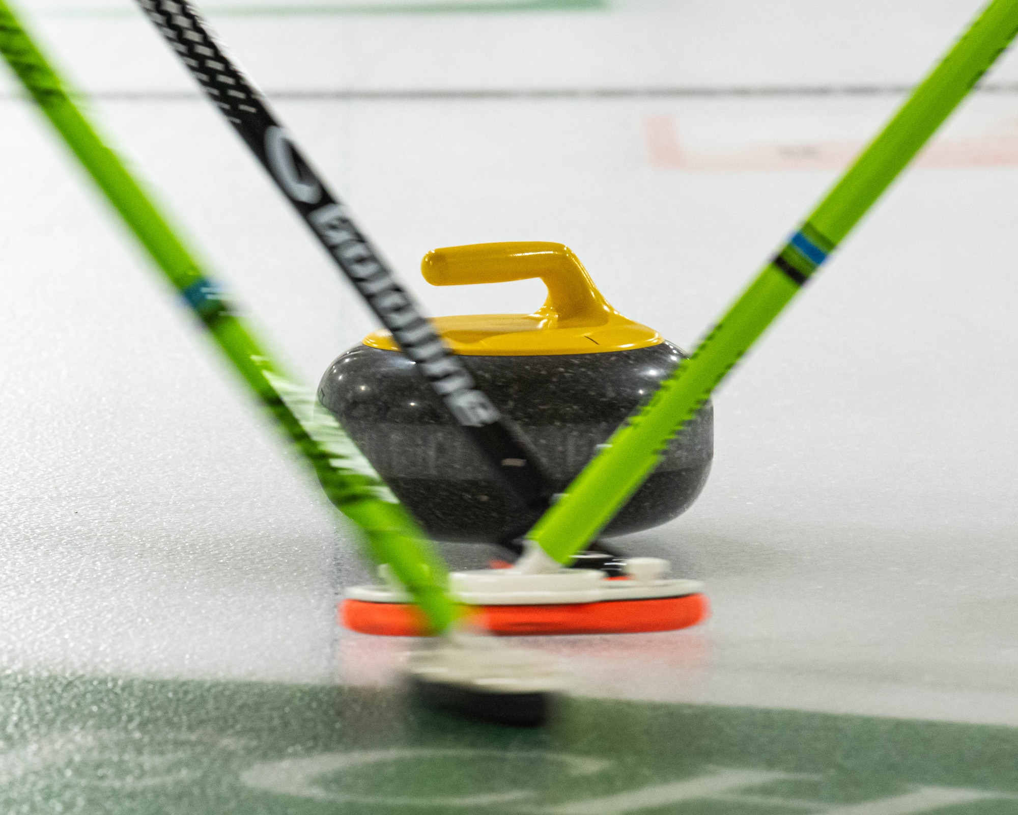 A curling stone slides across a sheet of ice at the Minot Curling Club, Minot, North Dakota, March 19, 2024. Players swept the ice in front of the stone to influence its movement and speed. (U.S. Air Force photo by Airman 1st Class Kyle Wilson)