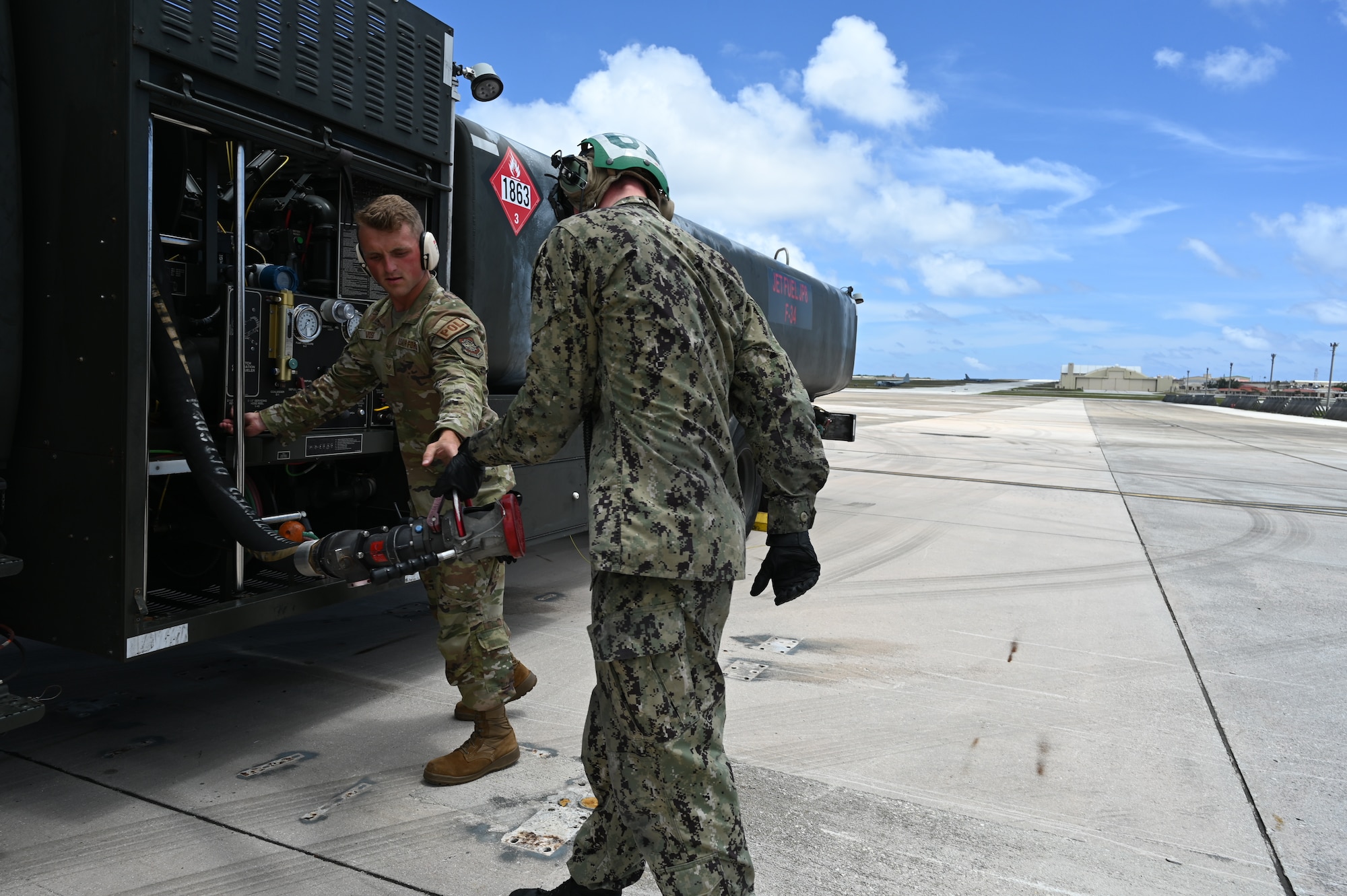An Airman and a Sailor work on pulling back the refueling equipment.