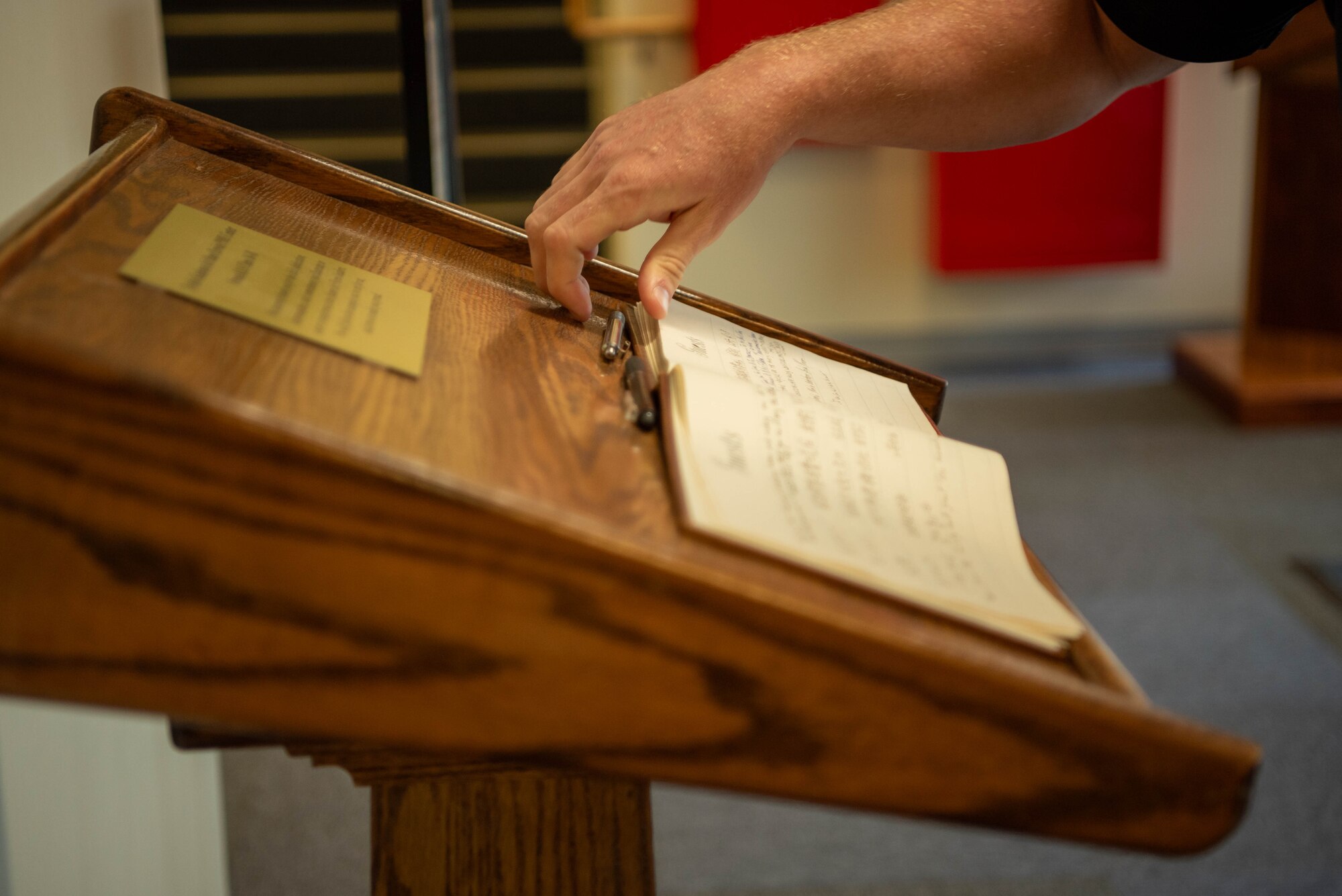 hand picks up a pen to sign a book on a podium