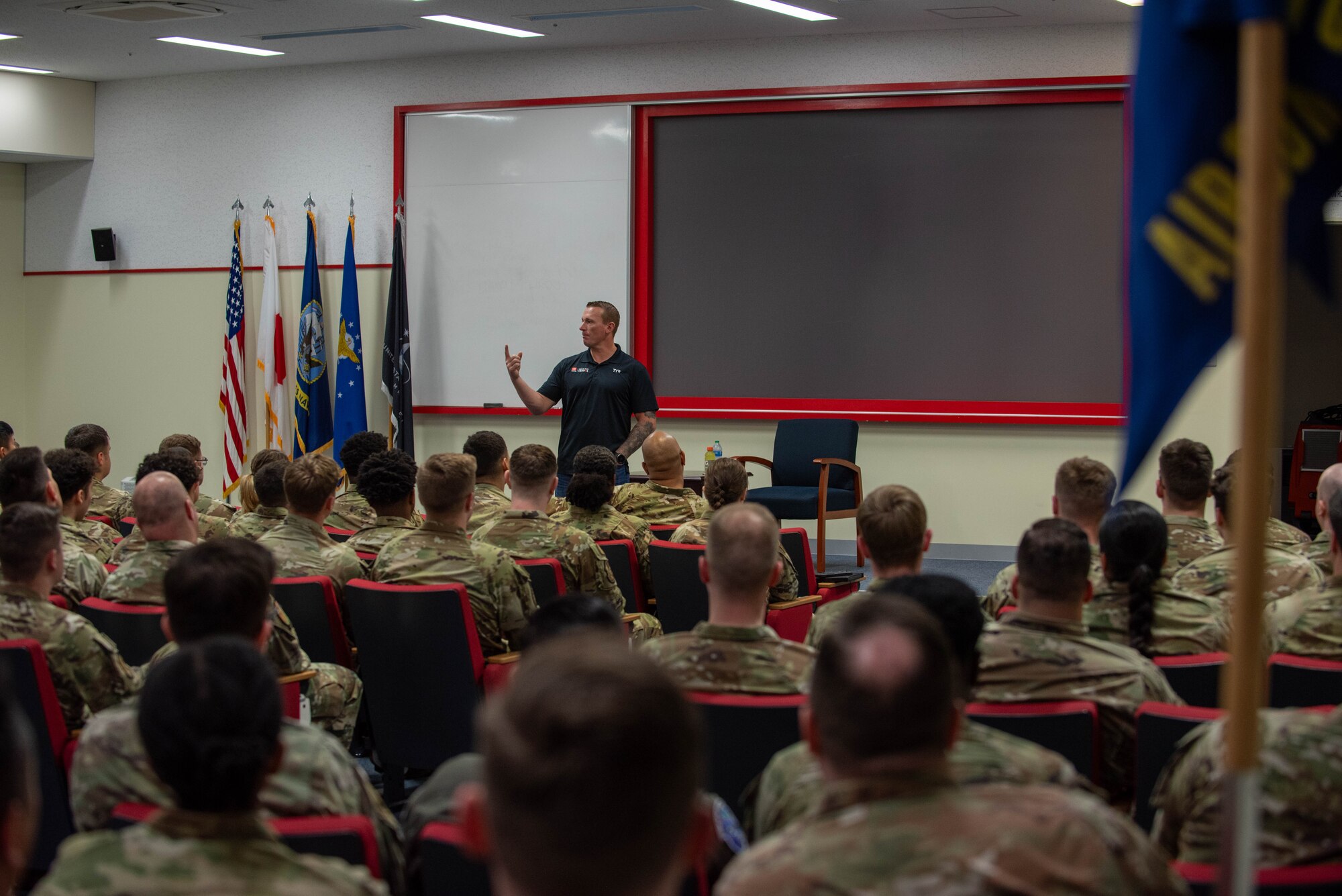 man speak in a big auditorium to a audience of military members