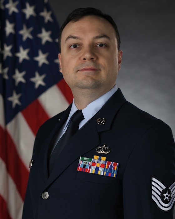 Official Photo of SSgt Ian O'Beirne,, regional band- saxophone.  SSgt O'Beirne is wearing blue service dress in front of the American flag.