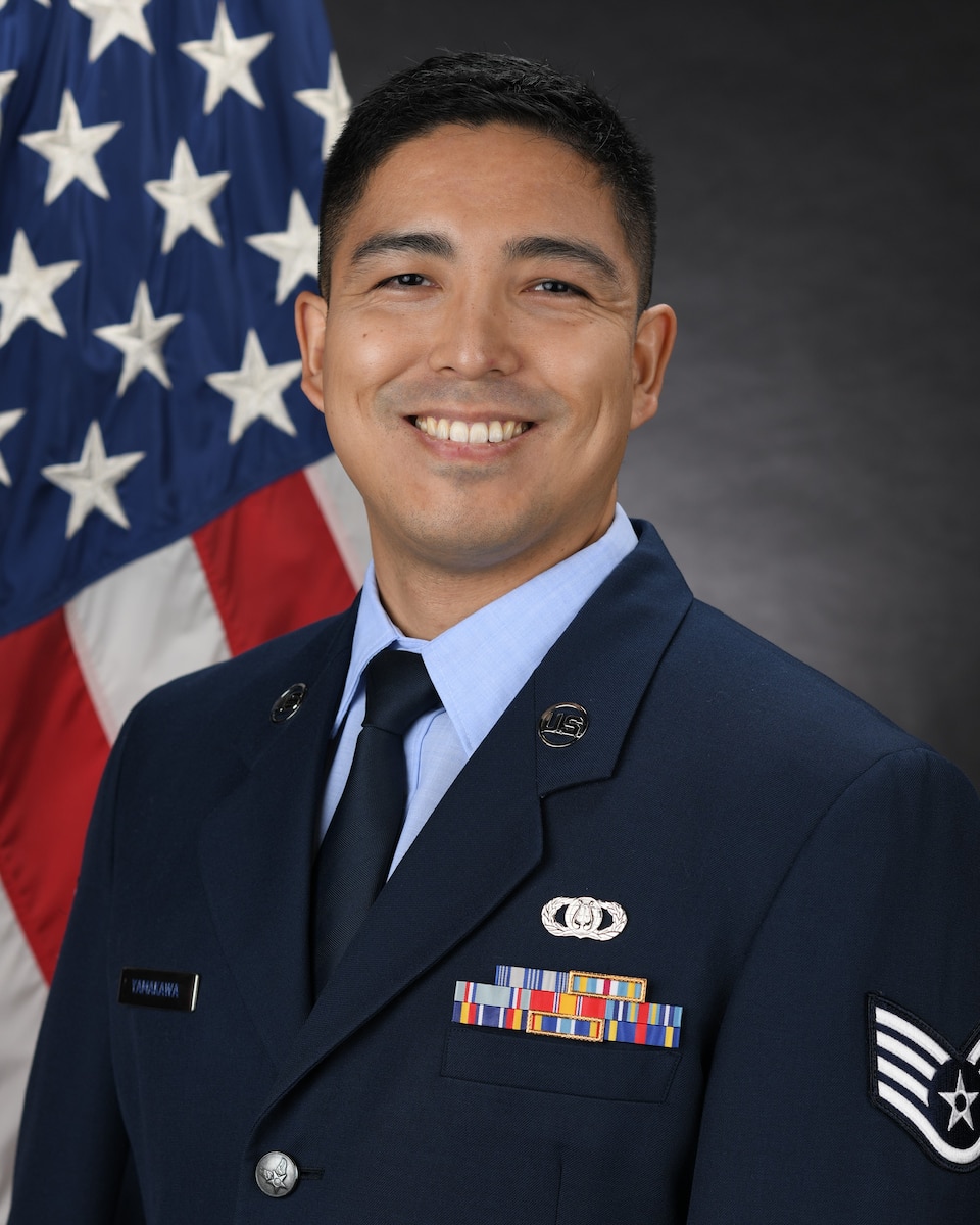 Official Photo of SSgt Ryu Yamakawa, regional band- guitar.  SSgt Yamakawa is wearing blue service dress in front of the American flag.