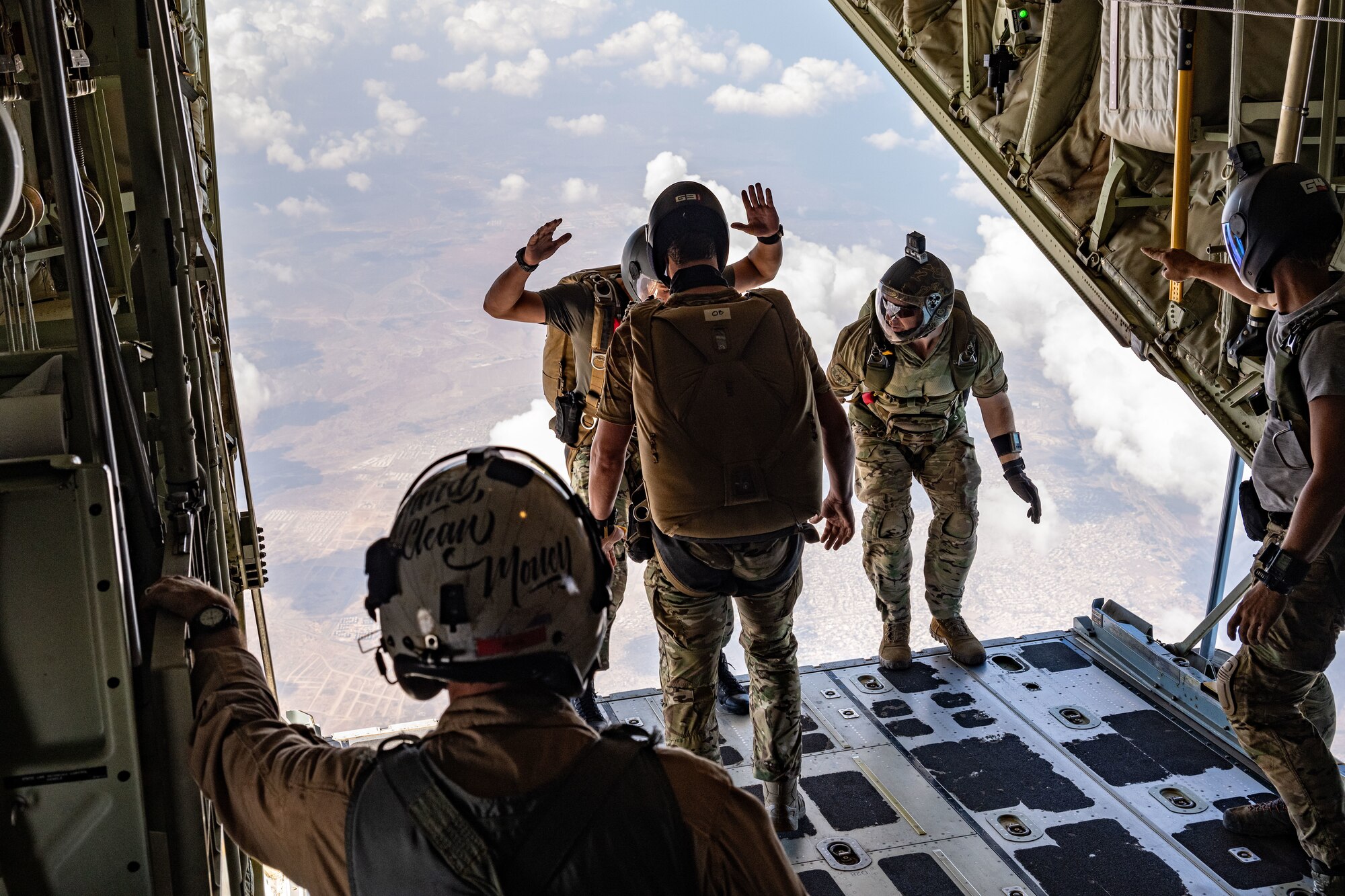 Service members jump from an aircraft cargo ramp to conduct parachute training.