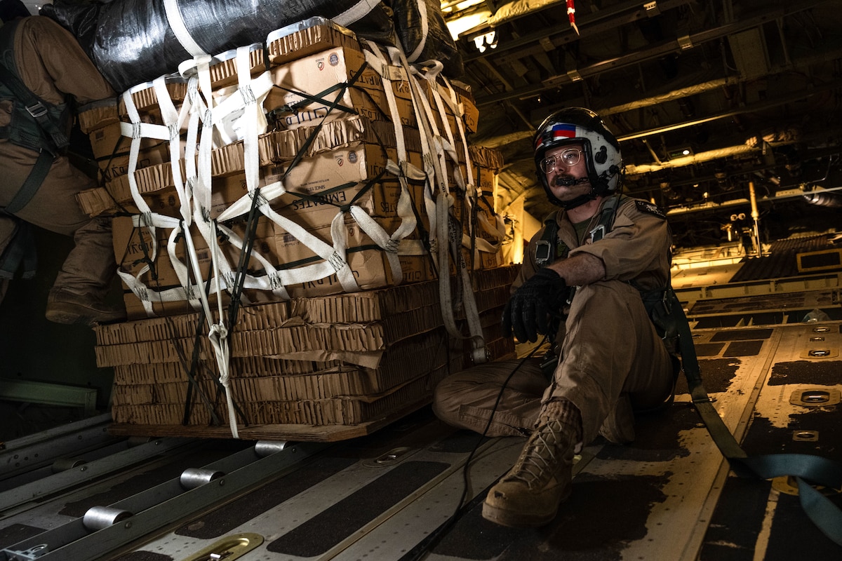 A Marine sits next to a cargo pallet on an aircraft.