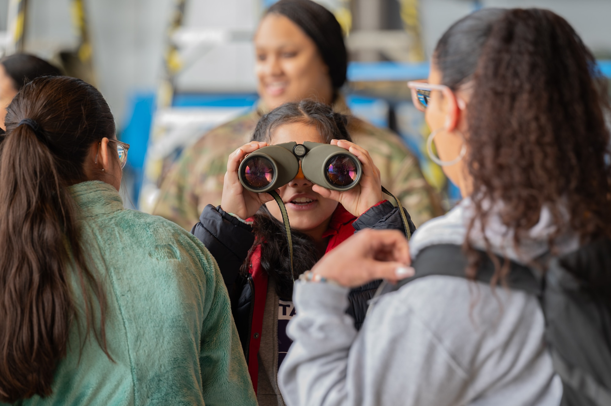 A Department of Defense Education Activity student looks through binoculars during a Fly Like a Girl event at Ramstein Air Base, Germany, March 20, 2024.