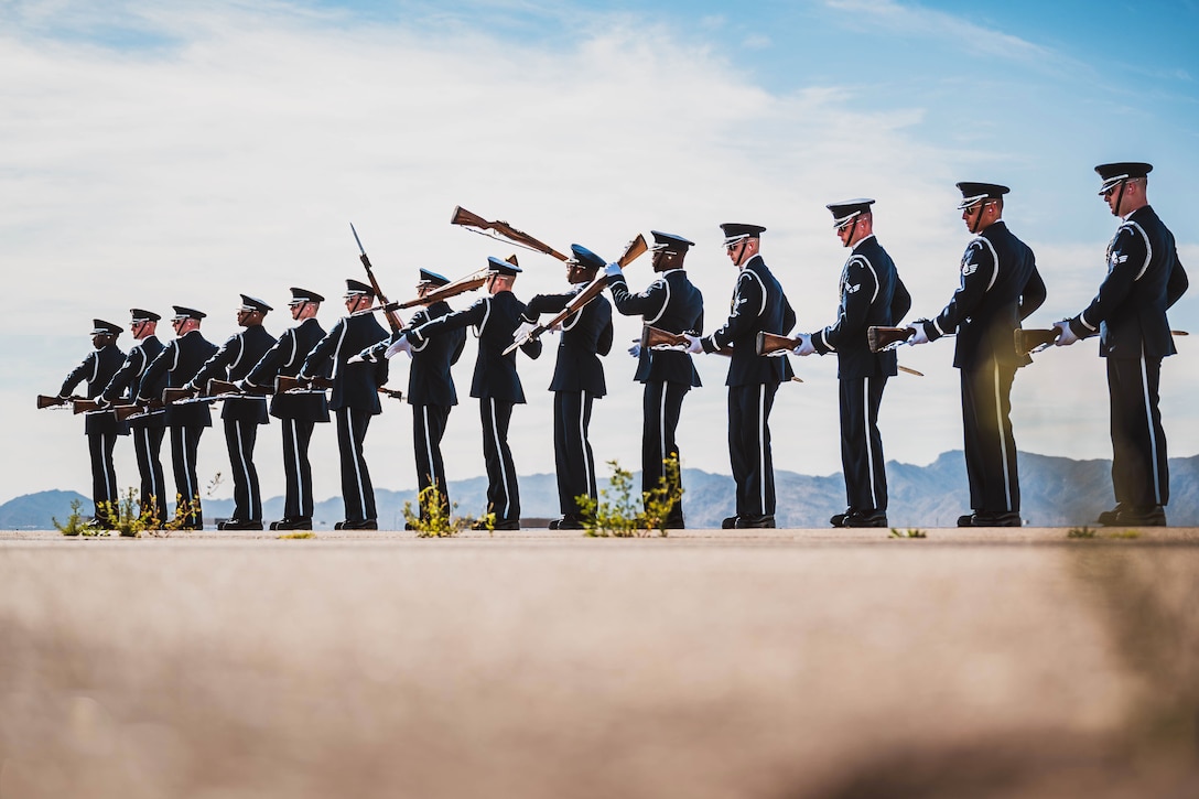 The Air Force Honor Guard stand in a straight line, performing a synchronized drill.