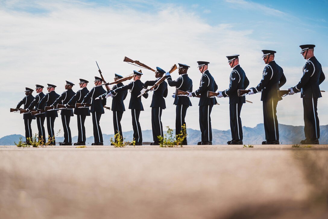 The Air Force Honor Guard stand in a straight line, performing a synchronized drill.