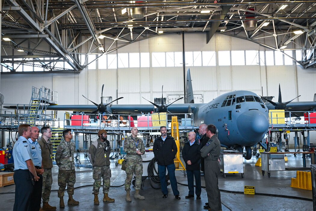 Uniformed personnel look around an aircraft hanger