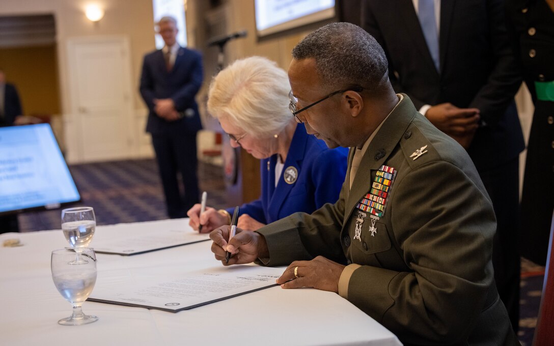Meg Bohmke, chairmen, Falmouth District, left, and U.S. Marine Corps Col. Michael L. Brooks, commanding officer, Marine Corps Base Quantico, and native of Virginia, right, sign the Intergovernmental Support Agreement during the Virginia Military Advisory Council at the Clubs at Quantico, Virginia, March 14, 2024. The VMAC holds quarterly meetings to explore issues impacting the quality of life for service members, their families, relations between the installations and surrounding civilian communities, and the effects on Virginia's growing infrastructure. (U.S. Marine Corps Photo by Sgt. Mitchell Johnson)
