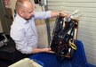 Chris Borrell, facilities operations specialist for U.S. Army Medical Logistics Command, tosses a box of old cables and other office supplies into a bin to be recycled March 25 at AMLC headquarters at Fort Detrick, Maryland. (C.J. Lovelace)