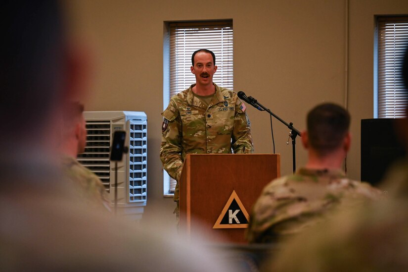 A military officer speaks from behind a podium.