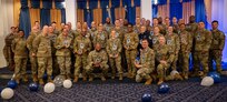 A large group of uniformed Airmen pose for a photo at a promotion ceremony.