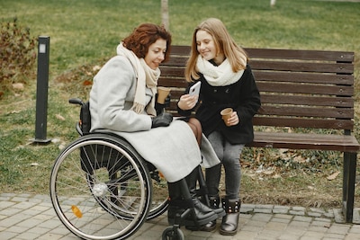Woman in wheelchair looks at her daughter's phone