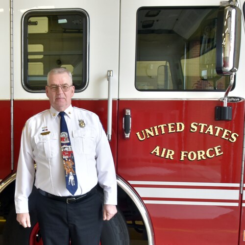 A man stands in front of a firetruck.