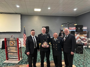 Four firemen in formal uniforms standing together.