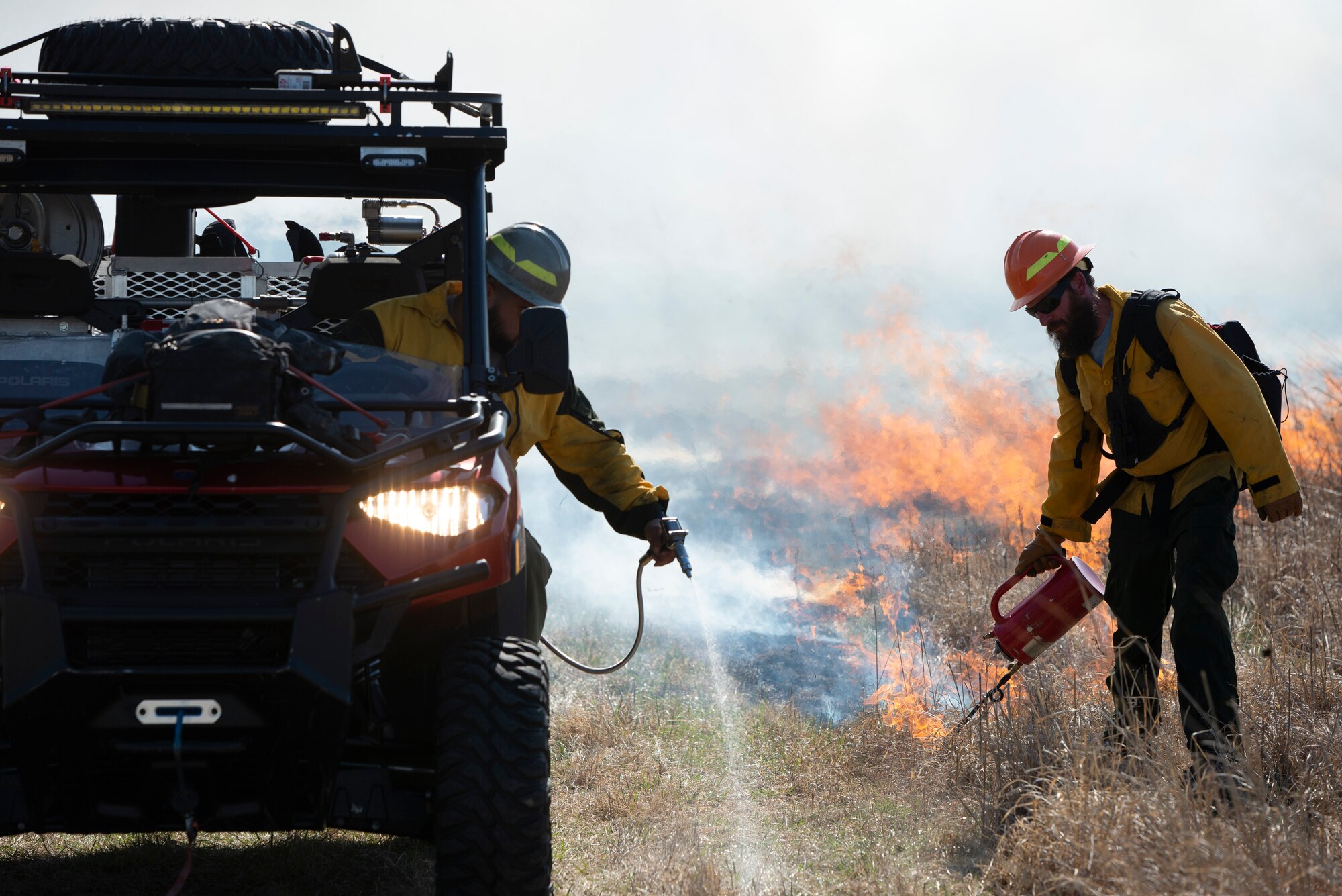 Two men work together to burn a field.
