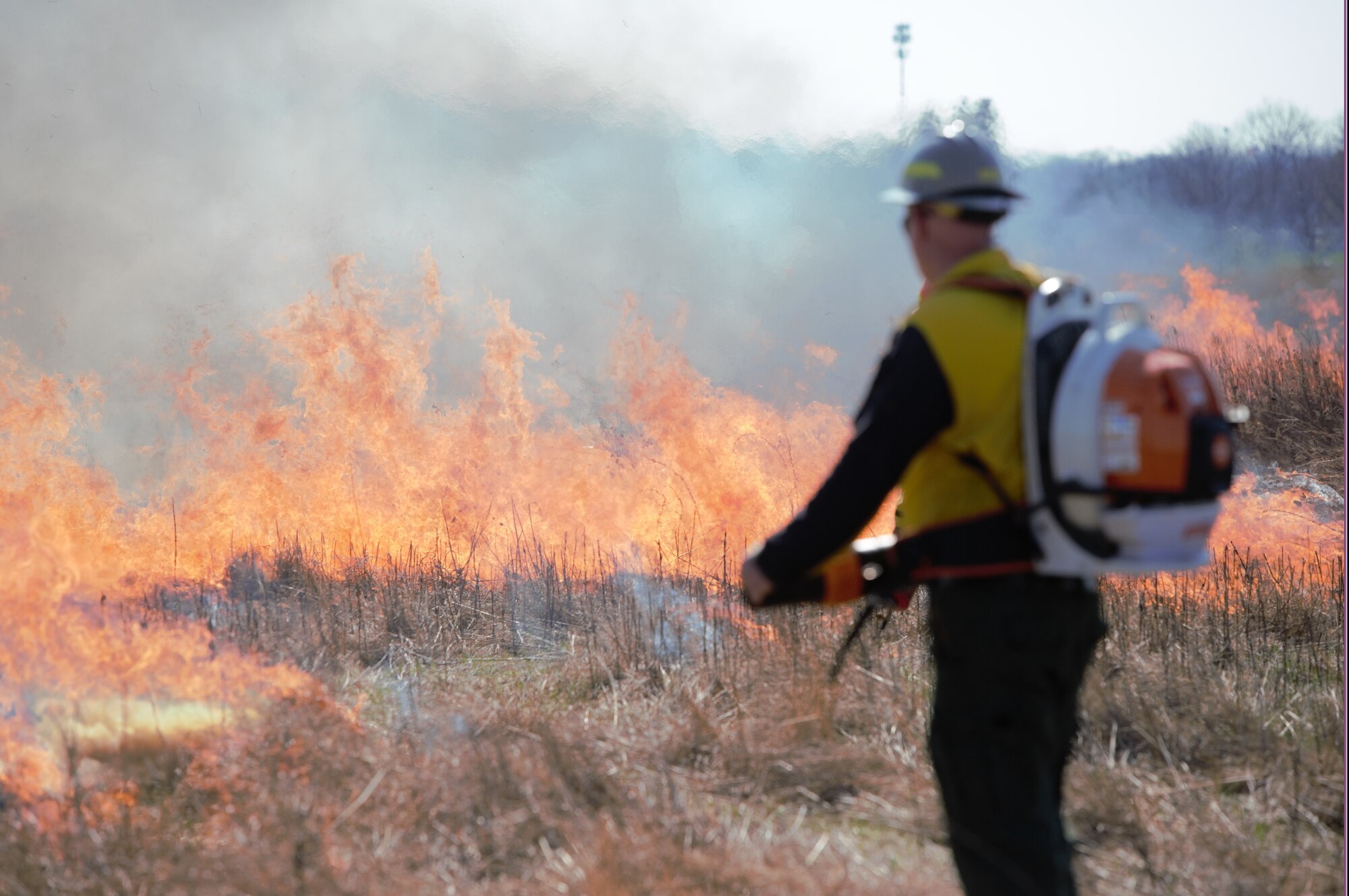 A man stares at a burning field.