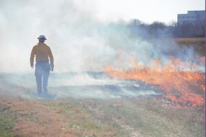 A firefighter walking through smoke.