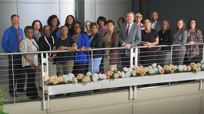 A group of men and women stand near a railing indoors