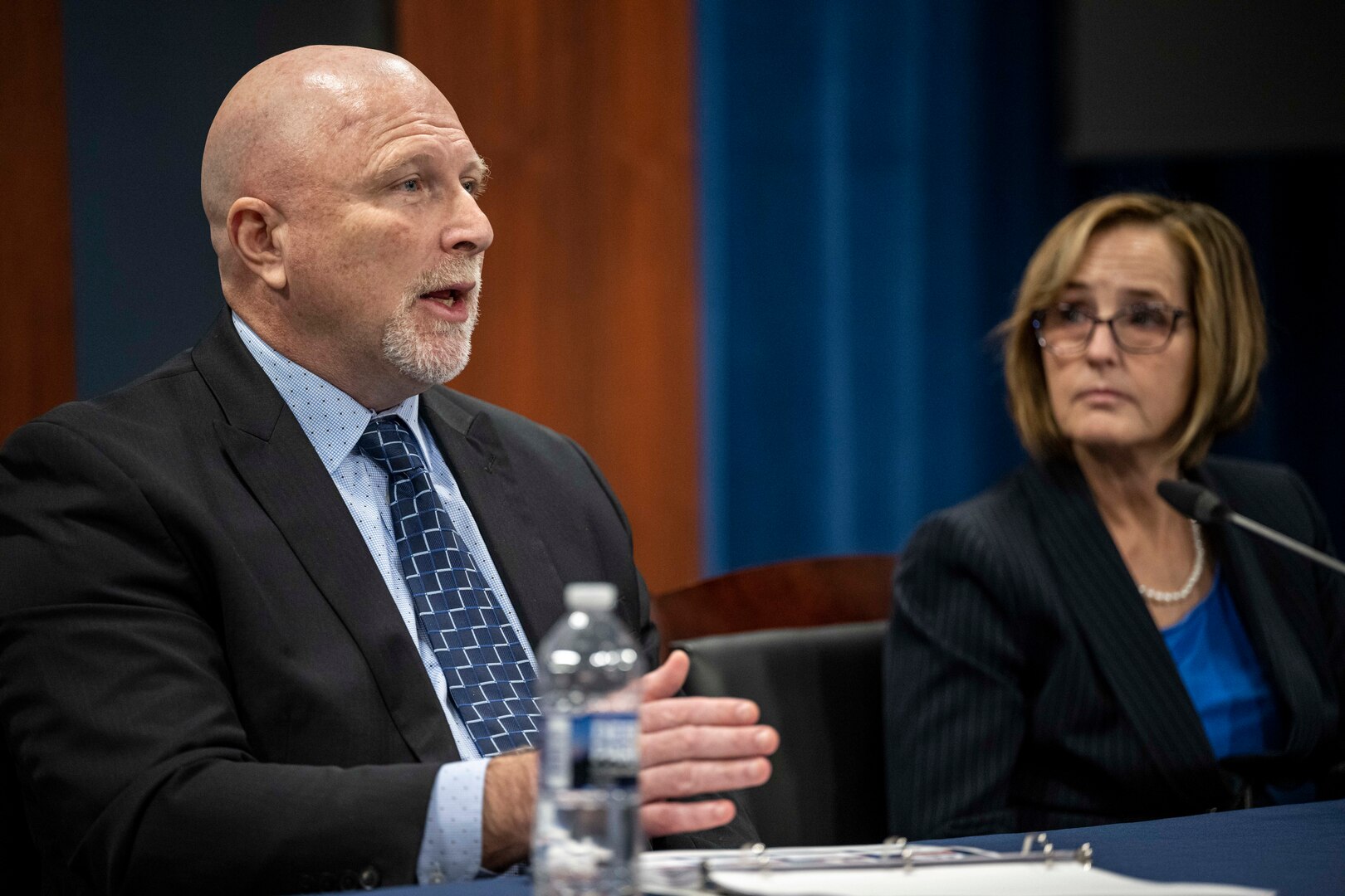 A man and woman wearing civilian attire sit at a table.